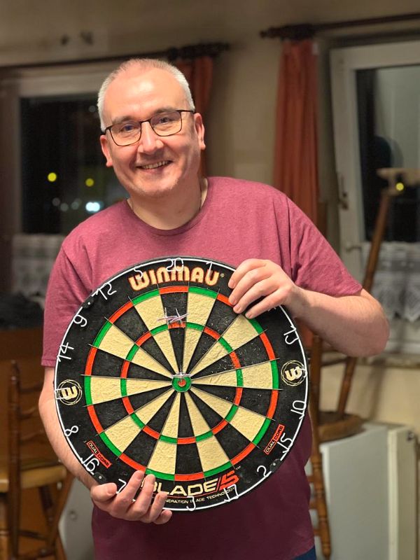 Mitglied hält ein neues Winmau-Dartboard in den Händen